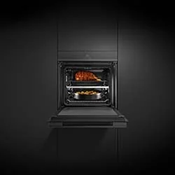Modern black oven in sleek kitchen, door open. Inside, a roast chicken on top rack and vegetables on bottom tray, creating a warm, inviting cooking scene.