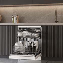 Open dishwasher in a modern kitchen with dark cabinets. It is loaded with neatly arranged dishes, cups, and silverware. The countertop holds oil bottles and a pepper mill.