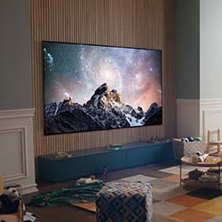 Living room with a large TV displaying a mountain and starry sky. Wooden accent wall, toys, and cozy seating create a warm, family-friendly atmosphere.