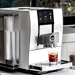 Modern espresso machine on a kitchen counter, dispensing coffee into a clear glass. Ambient lighting suggests a sleek and efficient design.