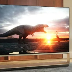 A TV screen displays a dramatic sunset with dinosaurs; a large dinosaur roars in the foreground as the sun sets in a cloudy sky, creating an intense scene.