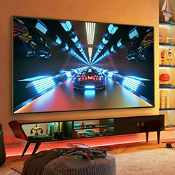 A large flat-screen TV displays a futuristic car racing scene with vibrant blue lights in a cosy living room with warm ambient lighting.