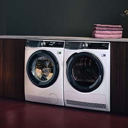 Black electric kettle emitting steam on a kitchen counter, surrounded by scones with jam and cream.