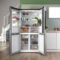 Open stainless steel refrigerator in a modern kitchen. The fridge is filled with fruits, vegetables, and containers, conveying freshness and organization.