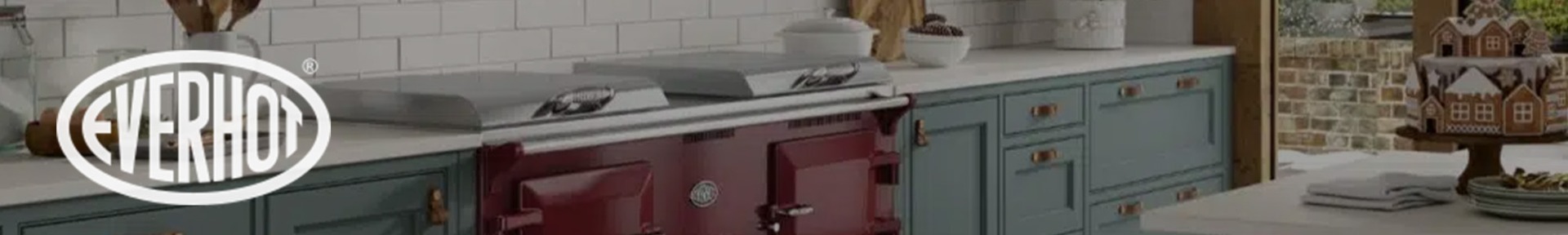 Modern kitchen with teal cabinets, a red vintage-style Everhot stove, and white subway tiles. Cozy holiday decor includes a gingerbread house and tree.