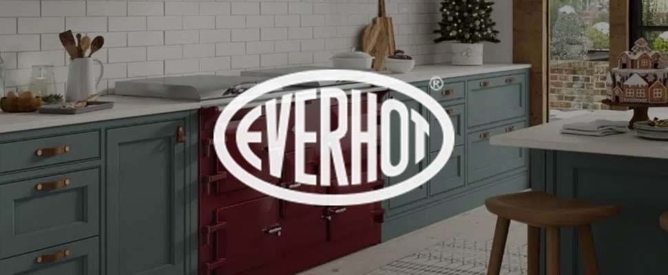 Modern kitchen with teal cabinets, a red vintage-style Everhot stove, and white subway tiles. Cozy holiday decor includes a gingerbread house and tree.