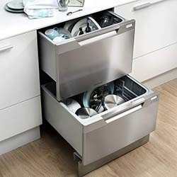 Two stainless steel dishwasher drawers, partially open, reveal clean dishes and glasses. The modern kitchen setting conveys efficiency and tidiness.