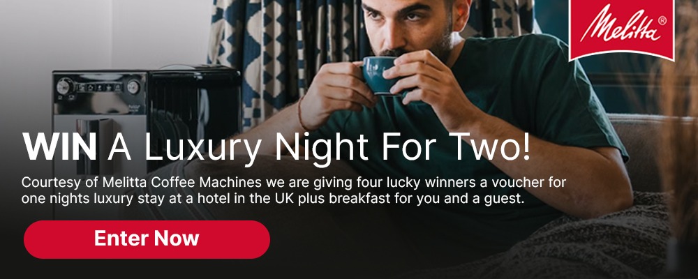 Man sipping coffee beside a Melitta coffee machine with text promoting a "Luxury Night for Two" contest. Red button reads "Enter Now."
